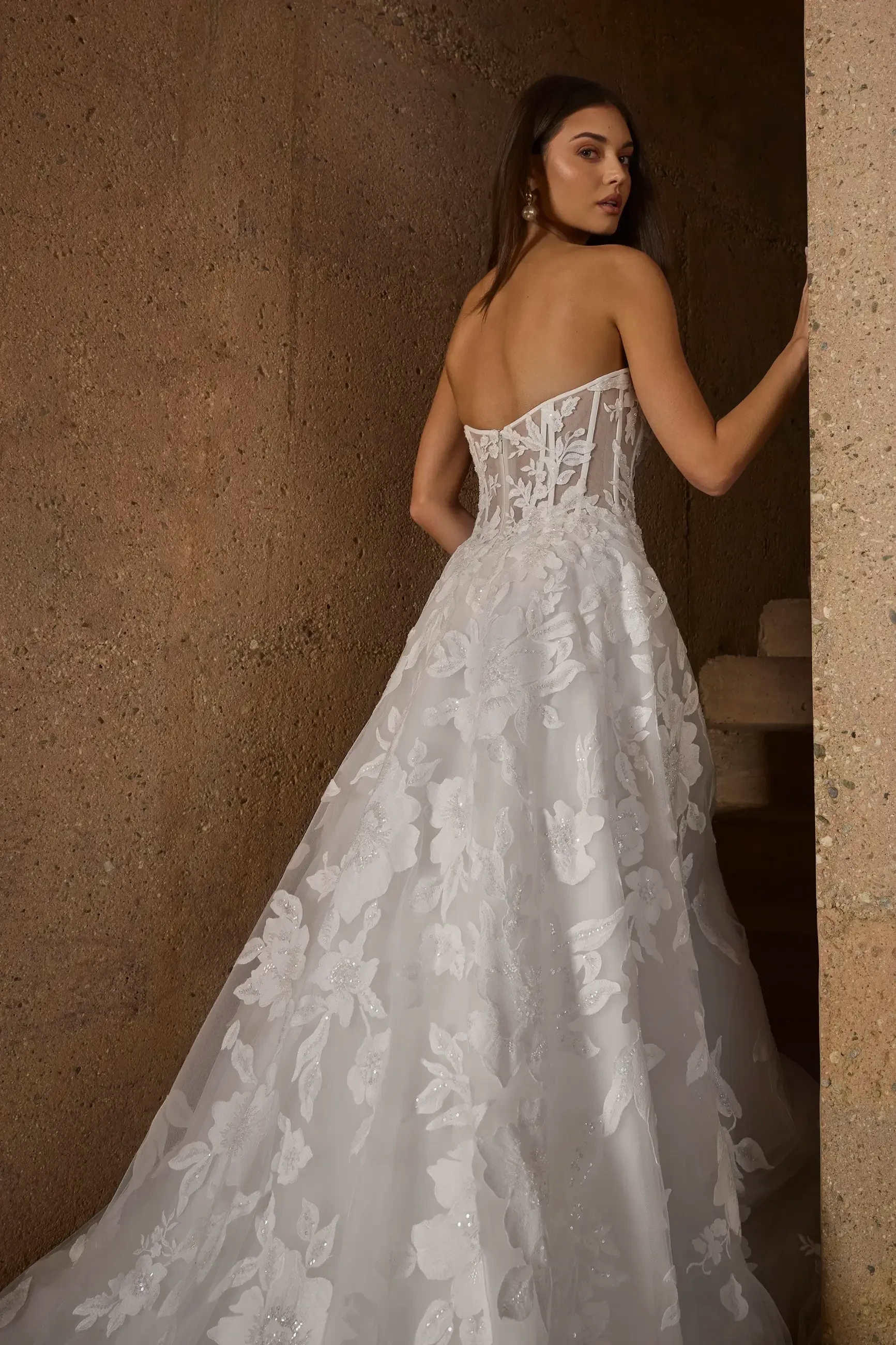 Model is wearing Morley, a strapless A-line gown with a sweetheart neckline, exposed boning, and a tulle skirt adorned with beaded lace appliqués.