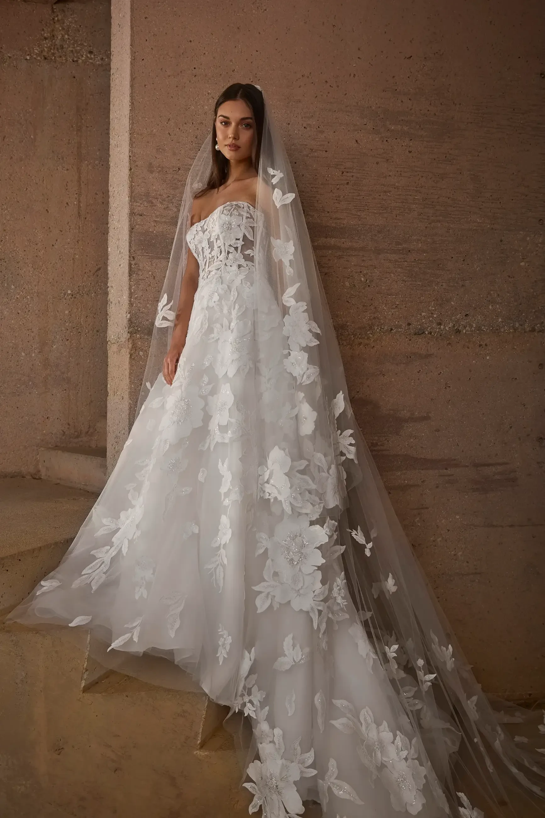 Model is wearing Morley, a strapless A-line gown with a sweetheart neckline, exposed boning, and a tulle skirt adorned with beaded lace appliqués.