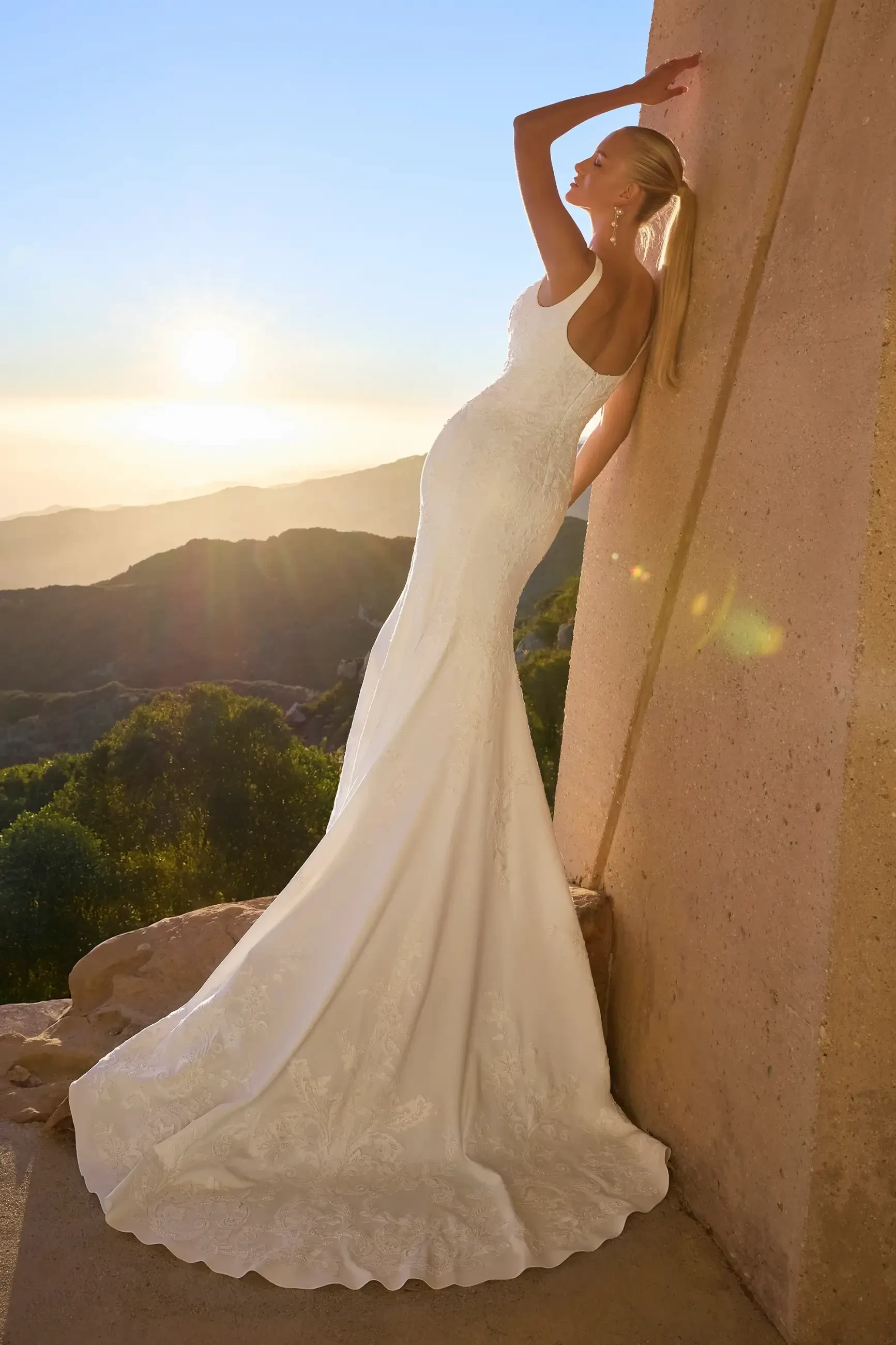 Model is wearing Malibu, a fit-and-flare gown with a square neckline, tank straps, and Italian crepe and stretch chiffon accented with beaded lace and sequins.