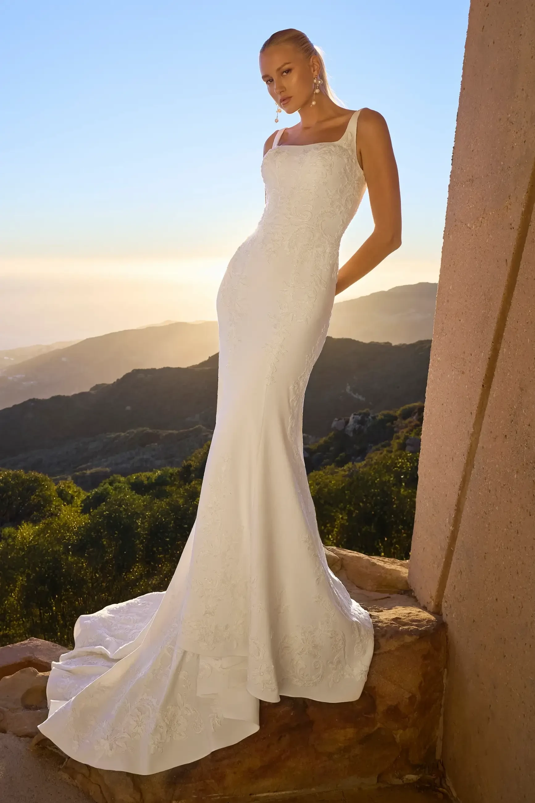 Model is wearing Malibu, a fit-and-flare gown with a square neckline, tank straps, and Italian crepe and stretch chiffon accented with beaded lace and sequins.