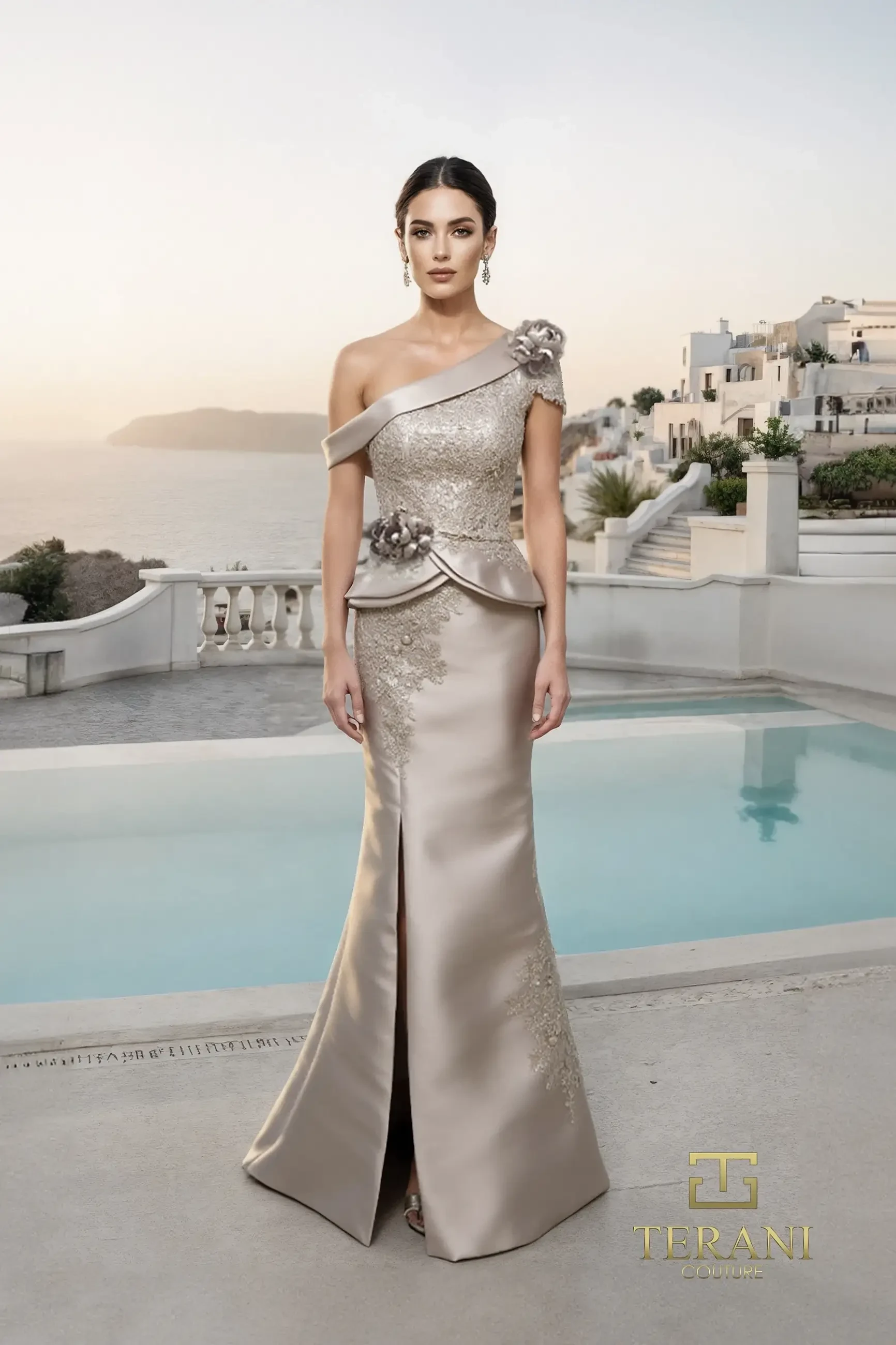 A woman wearing an elegant, one-shoulder, metallic-gold gown with floral embellishments stands by a pool with a scenic backdrop.